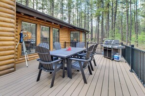 Une terrasse en bois avec une table et des chaises, un barbecue et un télescope.