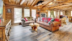A log cabin interior with a fireplace, leather sofas, wooden floors, and a stone wall. - Near Fishing & Hiking: Pinetop Log Cabin w/ Deck! (Pinetop)