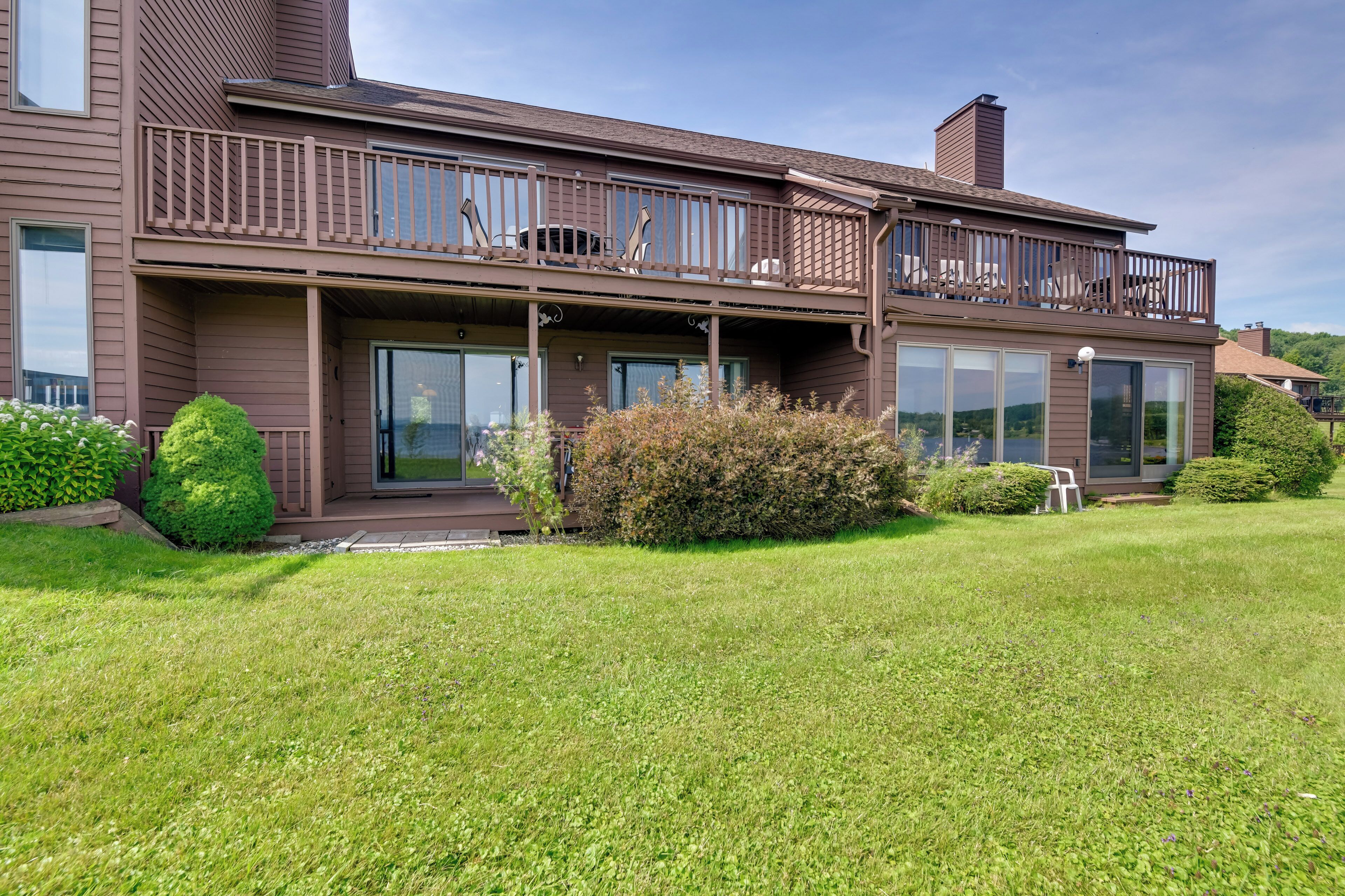 A two-story house with a balcony, large windows, and a well-maintained lawn.