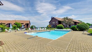 A swimming pool with lounge chairs and a brick building in the background. - Community Boat Dock: Lake Memphremagog Condo! (Newport Center)