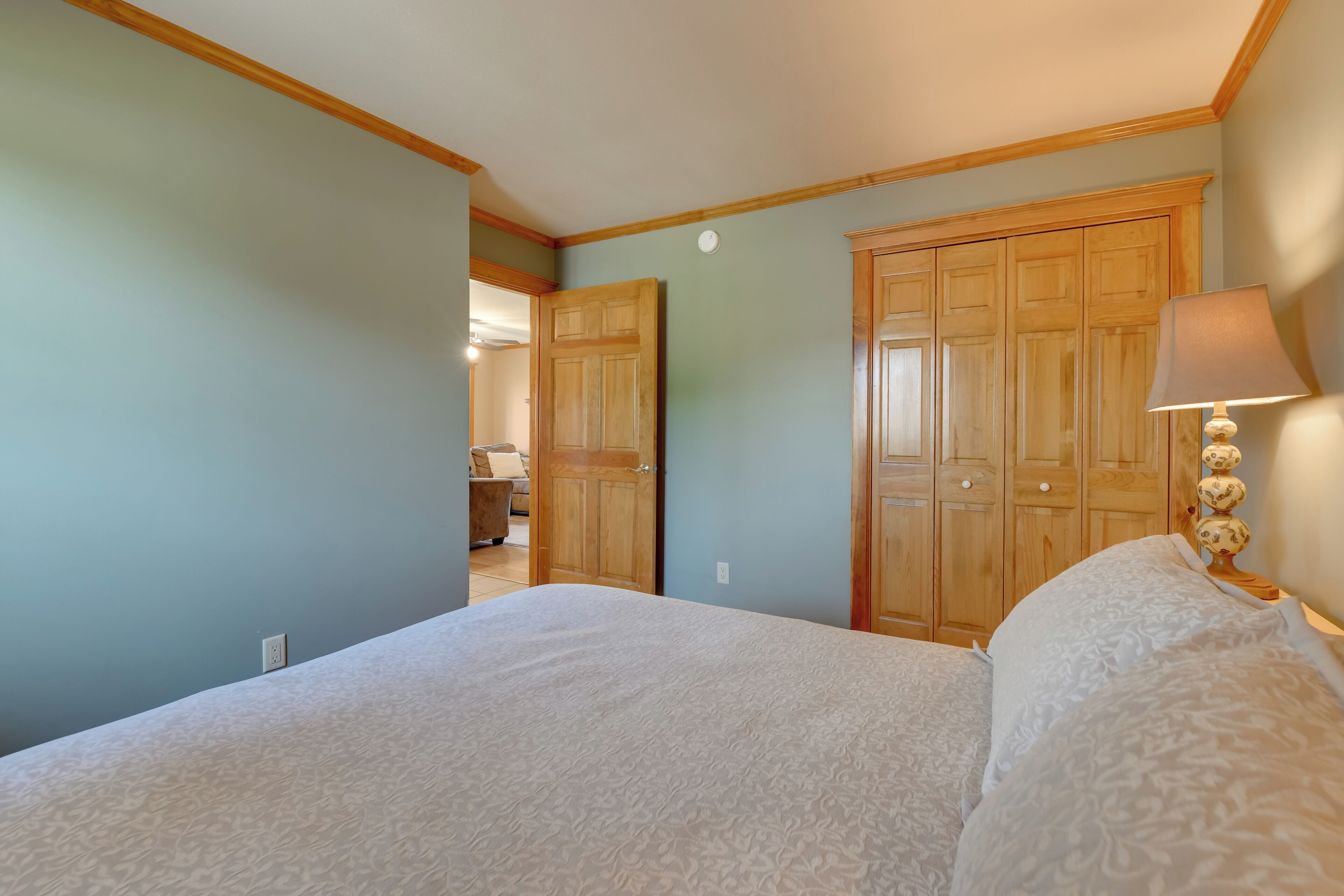 Un dormitorio con una cama grande, un armario de madera y una lámpara de noche.