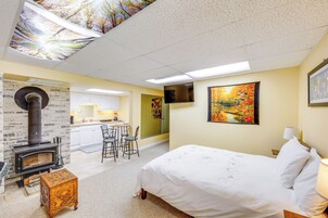 Un dormitorio con cama, una mesa de madera, chimenea, zona de cocina y una mesa de comedor con sillas.
