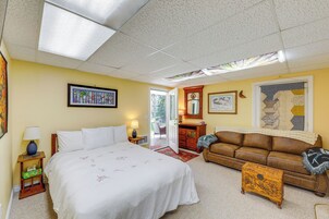 A bedroom with a bed, a sofa, a small table, and a door leading to a balcony.
