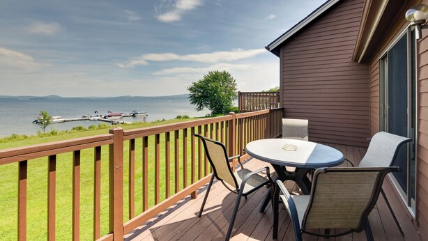 Een terras met tafel en stoelen met uitzicht op een meer met boten.