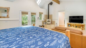 Ein Schlafzimmer mit einem großen Bett, einem Fernseher, einem Kamin und Blick ins Freie.
