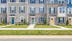 A row of townhouses with a stone facade, multiple windows with shutters, and a well-maintained lawn. - Easy Assateague Access: Bayside Family Retreat! (Berlin)