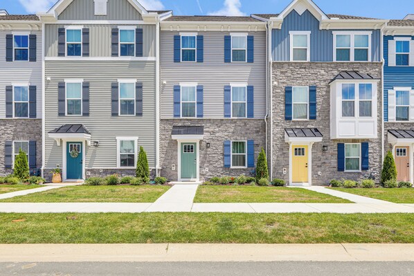 A row of townhouses with a stone facade, multiple windows with shutters, and a well-maintained lawn.