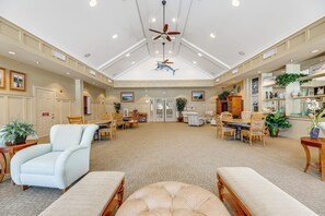 A spacious hotel lobby with a high ceiling, ceiling fans, and a central seating area with multiple chairs and tables.
