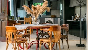 A dining area with a table, chairs, and a vase of pampas grass. - Villa Lilienne - Tranquil Escape With Private Garden Balcony (Rhodes)