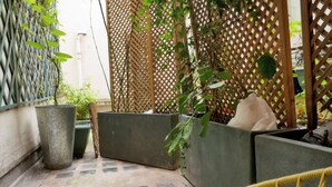 A courtyard with potted plants, a wooden lattice fence, and a tiled floor.