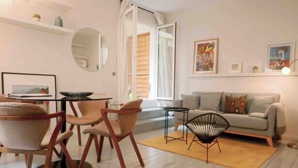 A modern living room with a sofa, chairs, a coffee table, and a dining area with chairs and a table.