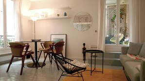 A modern living room with a sofa, two chairs, a small table, and a floor lamp. There is a window with a view of greenery outside.