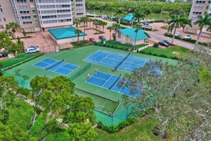 A tennis court surrounded by greenery and residential buildings. - Vanderbilt Beach Views from 2 Lanais (Naples)