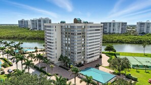 A high-rise hotel with multiple floors, a swimming pool, and tennis courts. - Vanderbilt Beach Views from 2 Lanais (Naples)