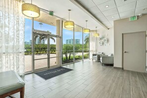 A hotel lobby with large windows, a reception desk, and a waiting area.