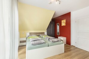 Un dormitorio con cama, mesitas de noche, armario y una pared de acento roja.