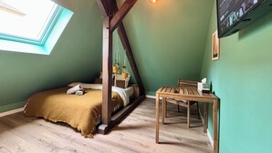 A cozy room with a bed, a wooden table, and a TV mounted on the wall. - Urban hut (Sarreguemines)