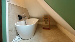 A modern bathroom with a freestanding bathtub, a towel rack, and a small wooden stool. - Urban hut (Sarreguemines)