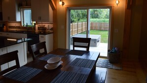A modern kitchen with wooden cabinets, a dining area with a table and chairs, and a sliding glass door leading to a backyard.