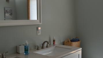 A bathroom with two sinks, a mirror, a toilet, and a basket on the floor.