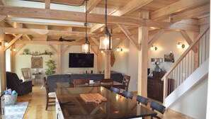 A spacious kitchen with a large island, wooden beams, and hanging pendant lights.