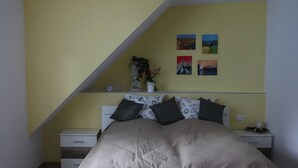 A bedroom with a bed, nightstands, a dresser, and a sloped ceiling. - Room 'Provence' with Shared Terrace and Wi-Fi (Birstein)