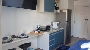 Una cocina moderna con campana extractora negra, armarios azules y refrigerador de acero inoxidable.