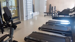 Un gimnasio con cintas de correr, máquinas de pesas y un espejo grande.