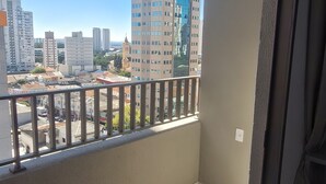 Un balcón con vistas a un paisaje urbano, que incluye edificios altos y un cielo despejado.