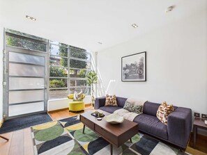 Ein modernes Wohnzimmer mit einer Couch, einem Couchtisch und einem großen Fenster mit Blick auf Grünflächen.