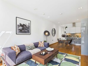 A modern living room with a sofa, coffee table, and a dining area with chairs and a table.