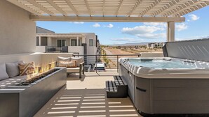 A modern outdoor patio with a fire feature, seating, and a hot tub.