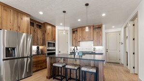 A modern kitchen with wooden cabinets, stainless steel appliances, and a central island with bar stools.