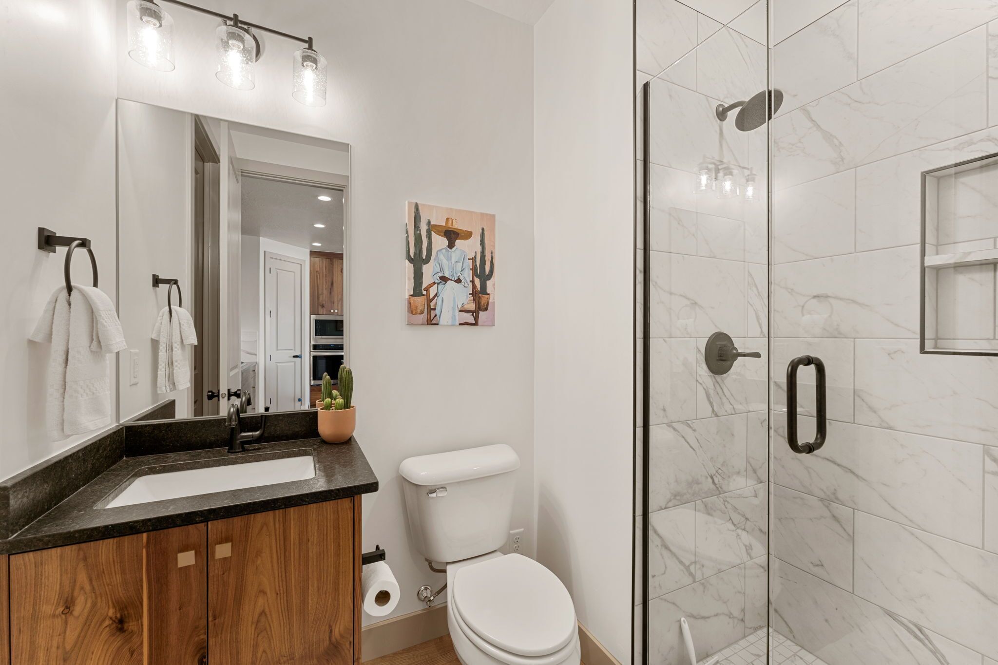 A modern bathroom with a glass-enclosed shower, a wooden vanity with a sink, and a toilet.