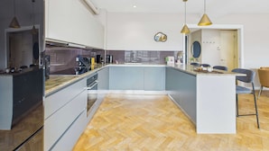 A modern kitchen with a herringbone floor, a central island, and pendant lighting.