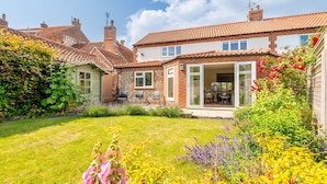 A residential property with a garden, a patio with outdoor seating, and a brick facade. - Creake Cottage, Burnham Market, Norfolk (Burnham market)