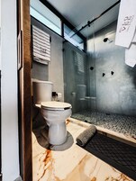 Un baño moderno con inodoro, cabina de ducha de vidrio y suelo de mármol.