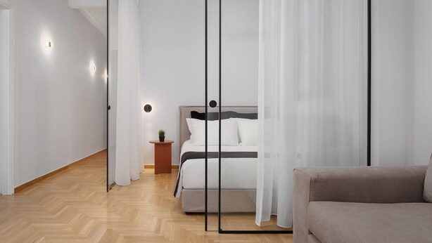 A modern bedroom with a bed, a small side table, and a sofa.