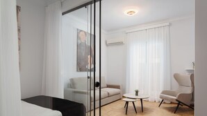 A modern living room with a glass partition, a sofa, a round table, and a chair.