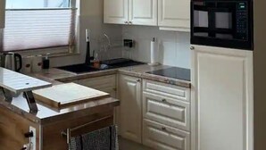 A small kitchen with white cabinets, a microwave, a sink, and a window with blinds. - Cozy vacation apartment Buttermarkt in Linz am Rhein (Linz am Rhein)
