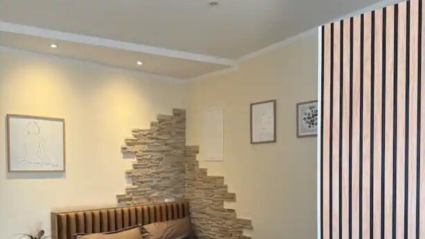 A modern bedroom with a large bed, a stone accent wall, and a wooden floor. - Cozy vacation apartment Buttermarkt in Linz am Rhein (Linz am Rhein)
