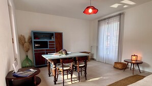 A living room with a dining table, chairs, a sofa, a lamp, and a window with curtains.
