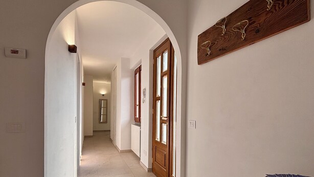 A hallway with a wooden door, a radiator, and a wall-mounted light fixture.