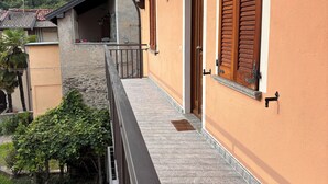 A balcony with a stone floor, wooden shutters, and a view of a mountainous landscape.