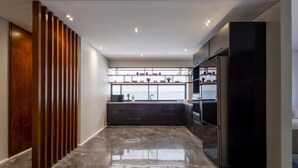 A modern kitchen with dark cabinetry, a black refrigerator, and a glossy marble floor. - Kennah Catalina | West Golf Extension, New Cairo (New Cairo)