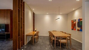 A modern dining area with a long wooden table and chairs, a TV, and abstract art on the wall. - Kennah Catalina | West Golf Extension, New Cairo (New Cairo)
