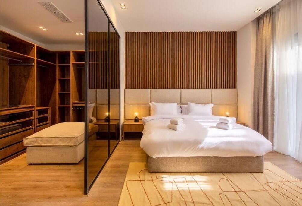 A modern hotel room with a large bed, a walk-in closet, and a wooden headboard.
