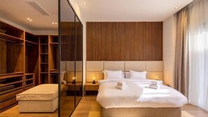 A modern hotel room with a large bed, a walk-in closet, and a wooden headboard. - Kennah Catalina | West Golf Extension, New Cairo (New Cairo)