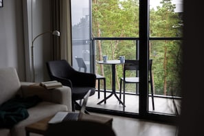 Ein modernes Zimmer mit einem großen Fenster, einem Sofa, einem Laptop und einem kleinen Tisch mit zwei Tassen.