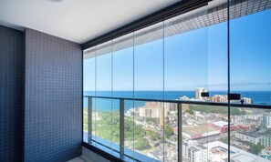 Un balcón con vista a la ciudad, ventanas amplias y un muro de azulejos.